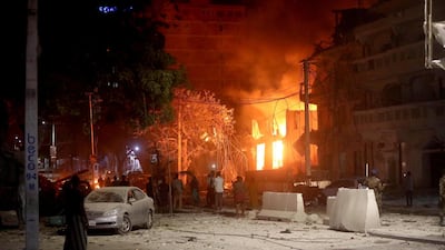 People look at flames at the scene where a suicide car bomb exploded targeting a hotel in the Somali capital. Reuters