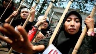 Indonesian activists sit inside a mock cell to represent abused migrant workers, outside the Saudi Arabian Embassy in Jakarta, Indonesia.