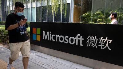 A man looks at his smartphone as he walks by the Microsoft office in Beijing. AP