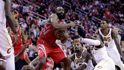 Houston Rockets guard James Harden, in red, looks to pass after coming up with a loose ball during the second half of an NBA basketball game against the Cleveland Cavaliers. Michael Wyke / AP Photo