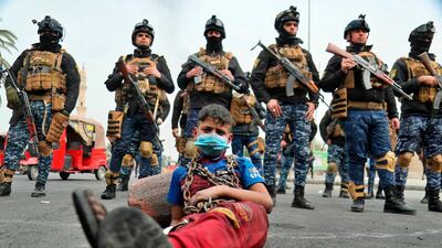 Anti-government protesters stage a sit-in while security forces stand guard during ongoing protests in downtown Baghdad, Iraq. AP Photo