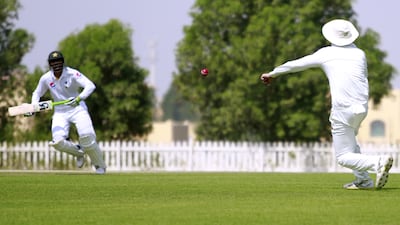 UAE player fileds the ball with Shan Maqsood of Pakistan looking on. Cricket match between Pakistan v UAE test match. Victor Besa for The National.