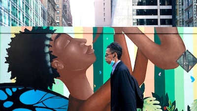 People walk past a Black Lives Matter (BLM) 80-foot-mural (24-meter) unveiled by ArtBridge on 6th Avenue in New York City. AFP