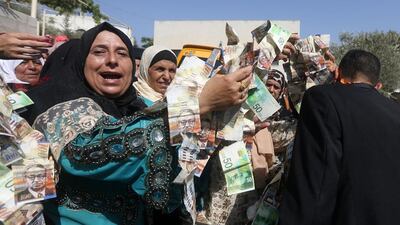 Palestinians decorate a groom with garlands of banknotes given by guests during a wedding in the village of Salem, east of the occupied West Bank city of Nablus, on July 31, 2016. Jaafar Ashtiyeh / AFP