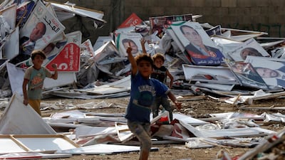 Children gesture as they collect wood from parliamentary candidates' posters, which were removed by the municipality after the results of the parliament elections were announced in Amman, Jordan. Reuters