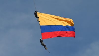 Air Force members Jesus Mosquera and Sebastian Gamboa hang from an helicopter as they wave a Colombian flag as part of a performance during the Flower Festival in Medellin, Colombia, on August 11, 2019. According to the Colombian Air Force, both men accidentally died after falling down when they were still hanging from the aircraft before landing at a local airport. AFP / JOAQUIN SARMIENTO