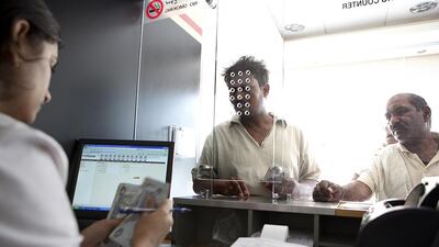 Cashier Rashmi D’Souza helps customers exchange money at a UAE Exchange branch on Hamdan Street in Abu Dhabi. Silvia Razgova / The National