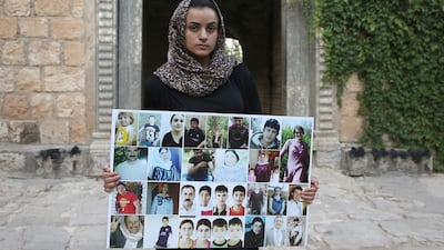 Ashwaq Haji, a Yazidi woman used as a sex slave by ISIS, holds portraits of victims of the extremist group from her village of Kocho near Sinjar. AFP