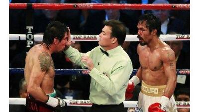 Manny Pacquiao, right, looks on as Laurence Cole, the referee, checks Antonio Margarito after Pacquiao wanted the fight stopped.