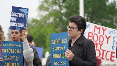 A woman holds a sign that reads: Catholics support abortion access in front of the Supreme Court. Willy Lowry / The National