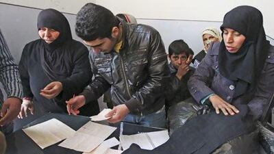 A worker inspects the list of names registered to receive new and second-hand clothes as part of humanitarian aid in Aleppo last week. A multi-million dollar aid programme for Syria, funded by the UN and implemented in association with the Syrian government, has drawn heavy criticism from the opposition. Muzaffar Salman / Reuters