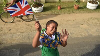 A girl holds a Union Jack flag as she cheers for Britain's Prince Harry and his wife Meghan, Duchess of Sussex as their convoy from Fua'amotu airport in Tonga passes by. Prince Harry and his pregnant wife Meghan left Fiji after a three-day official visit and arrived in Tonga as part of their tour of Australia and the South Pacific. AFP