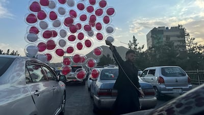 A vendor sells balloons amid traffic on a busy street in Kabul on September 16, 2024. (Photo by Wakil Kohsar / AFP)