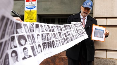 Paul Hudson, whose daughter Melina was one of the victims in the Pan Am Flight 103 bombing, holds up a banner with pictures of other victims outside the federal court. Getty / AFP