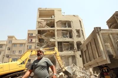 People walk past damaged houses after an Israeli air strike in Tehran on June 26. EPA