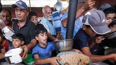 People queue to receive meals from a charity kitchen in the central Gaza Strip. AFP