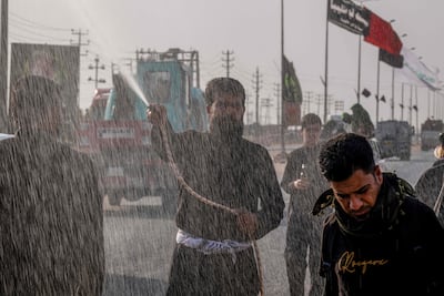 A man sprays Shiite pilgrims with water as they make their way towards Karbala and temperatures rise across Iraq. AFP