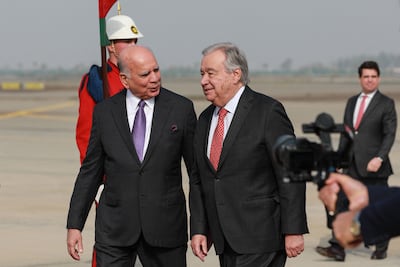 Iraq's Foreign Minister Fuad Hussein (L) walks alongside UN Secretary General Antonio Guterres upon the latter's arrival in Baghdad on December 13, 2025. AFP