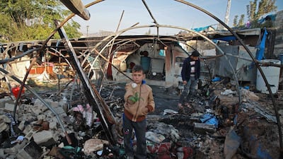 A Syrian boy holds a rose inside a charred tent following Syrian regime bombardment on a makeshift camp in the village of Qah near the Turkish border in the northwestern Idlib province on November 21, 2019. AFP