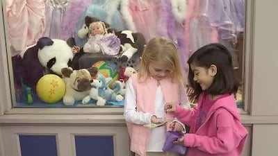 Two girls count their spending money in front of a toy store. Giving your child an allowance is a financial foundation.