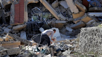 A Lebanese man collects books from a house that was destroyed by an Israeli airstrike, in Mansouri village, south Lebanon, on Wednesday. AP