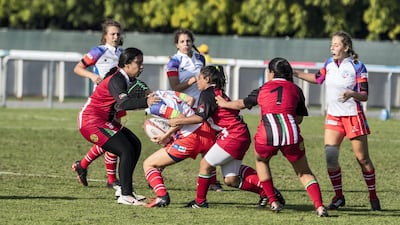 Al Maha players make a tackle on an opposing player.