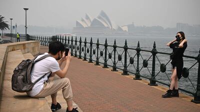 Tourists wearing masks take photos as the Sydney Opera House is enveloped in haze. AFP