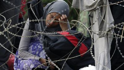 A migrant stands behind the barbed wire set by Macedonian police to stop thousands of migrants entering Macedonia illegally from Greece, near the southern Macedonian town of Gevgelija on August 22. Darko Vojinovic / AP