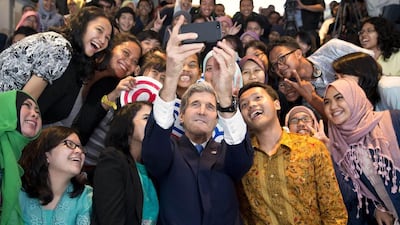 US Secretary of State John Kerry takes a photo with a group of students before delivering a speech on climate change in Jakarta, Indonesia, on February 16, 2014. Kerry will issue a clarion call for the world to do to more to combat climate change, warning the planet is being pushed to “a tipping point of no return”. Evan Vucci / AFP photo