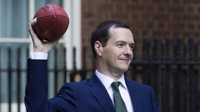 Britain's George Osborne throws an American football after meeting with former NFL players and current team owners on Friday at 11 Downing Street. Justin Tallis / AFP / October 2, 2015