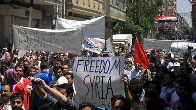 Syrian protesters holding banners as they march during a demonstration in Homs.