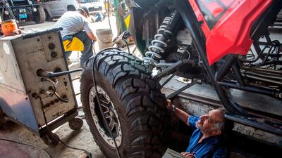 A mechanic works on Jacques Barron and his son and co-driver Lucas Barron's UTV (Utility Task Vehicle) at a workshop in Lima. AFP
