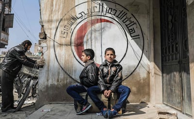 Years later, children in front of a Syrian Red Crescent logo in Eastern Ghouta, where the Assad regime used sarin gas. AFP