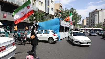 A woman holds Iran's national flag at Enghelab Square in Tehran. EPA
