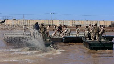 (FILES) In this file photo taken on March 06, 2017 international coalition forces and Iraqi soldiers instal a floating bridge at the Taji camp, north of Baghdad, during a training session. Katyusha rockets targeted an Iraqi airbase north of Baghdad hosting US-led coalition forces, the Iraqi military said on January 14, 2020 in the latest attack on installations where American troops are deployed. The statement from Iraq's military did not say how many rockets had hit Camp Taji but reported that there were no casualties. / AFP / SABAH ARAR