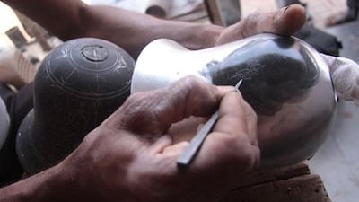 Midur Rauf engraves a pattern outline on to the surface of a vase.