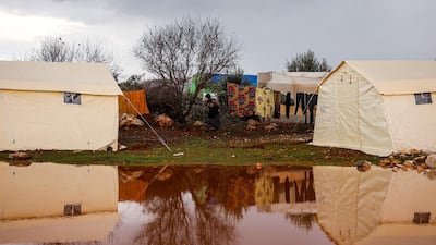A woman walks past hanging laundry lines between tents at a flooded camp for displaced Syrians near the village of Killi in the north of the northwestern Idlib province on February 8, 2020. / AFP / AAREF WATAD