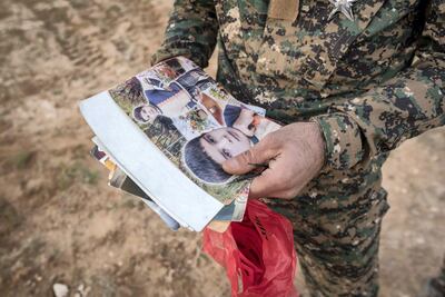 A Syrian Democratic Forces fighter searches the possessions of civilians who fled the last pocket of ISIS territory in Syria outside Baghouz. Campbell MacDiarmid / The National