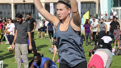 Dozens of people take part in an aerobics class on the field at Dubai Festival City. Chris Whiteoak / The National