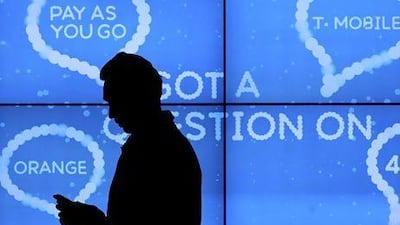 An employee adjusts a handset in front of a screen advertising different mobile services on offer at a shop near London. Jason Alden / Bloomberg News