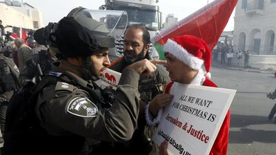 An Israeli soldier argues with a Palestinian protester dressed as Santa Claus during a demonstration in the West Bank city of Bethlehem / EPA
