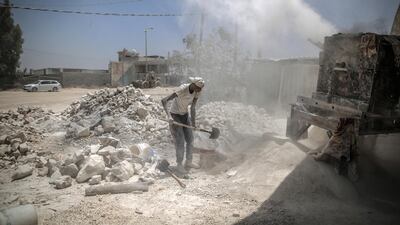 Workers with the rubble of buildings destroyed during the May rocket attacks. Sanad Latefa for The National