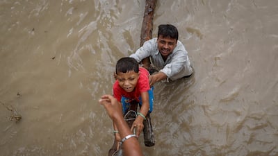 A man helps his son clamber on to a flyover under construction, after being displaced by rising water levels in New Delhi. Reuters