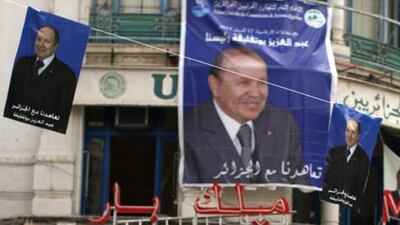 Algerian youths walk past posters of Algerian president Abdelaziz Bouteflika and other candidates in the presidential elections, in the center of Algiers on April 15. Patrick Baz / AFP Photo