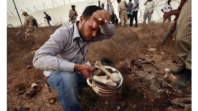 A man collects human remains from a mass grave in Tripoli on Sunday. Libya's interim authorities said the grave held the bodies of more than 1,270 people killed by Muammar Qaddafi's security forces in a massacre in 1996 at Abu Salim prison. Suhaib Salem / Reuters