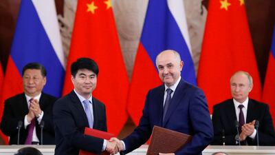 Guo Ping, deputy chairman of Huawei foreground left, shakes hands with Russian President of MTS mobile network operator, Alexei Kornya as Russian President Vladimir Putin, right, and Chinese President Xi Jinping attend a signing ceremony following their talks in the Kremlin in Moscow. AP