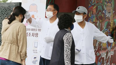 Officials of a Buddhist temple check congregants' temperatures before allowing entry to a temple on South Korea's southern resort island of Jeju, South Korea. EPA