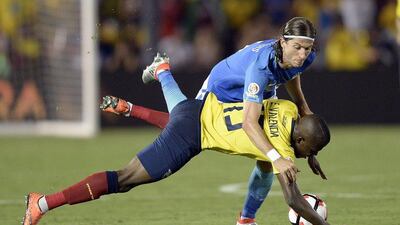 Brazil left-back Felipe Luis, in blue, bundles Ecuador's Enner Valencia to the ground. Kevork Djansezian / Getty Images