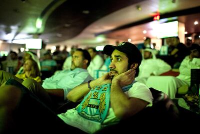A UAE-resident follows a football match on TV, with other fans, in Zayed Sports City, Abu Dhabi, on April 30, 2012. Silvia Razgova / The National