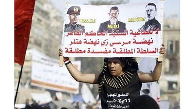 A Tahrir Square protester's sign ("No to a dictator …") expresses outrage against Egypt's President Mohammed Morsi. The president must renounce his claim to extraordinary powers, a reader says. Mohamed Abd El Ghany / Reuters